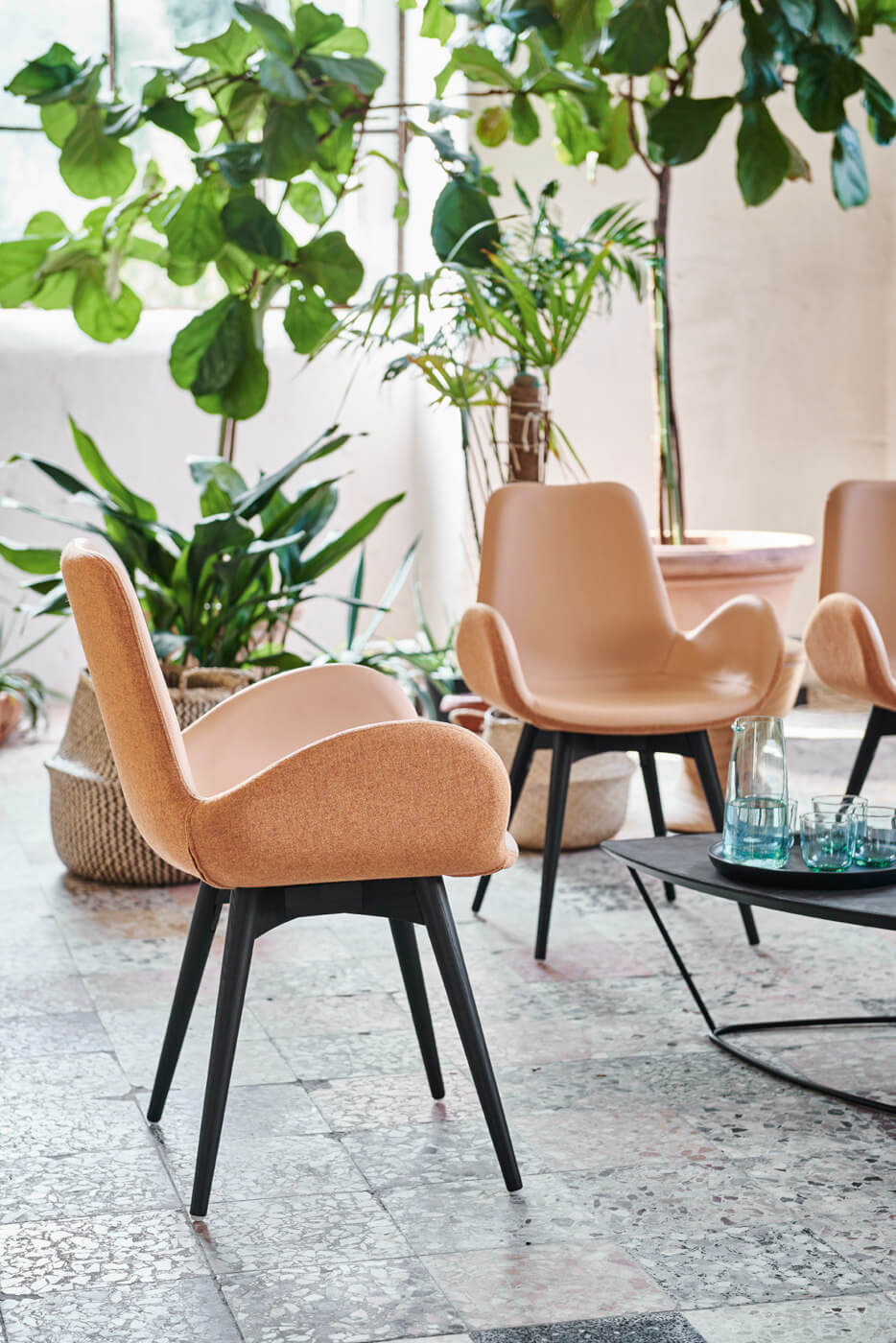 Dalia armchair with four-leg base in wood and cover in leather and pink fabric.