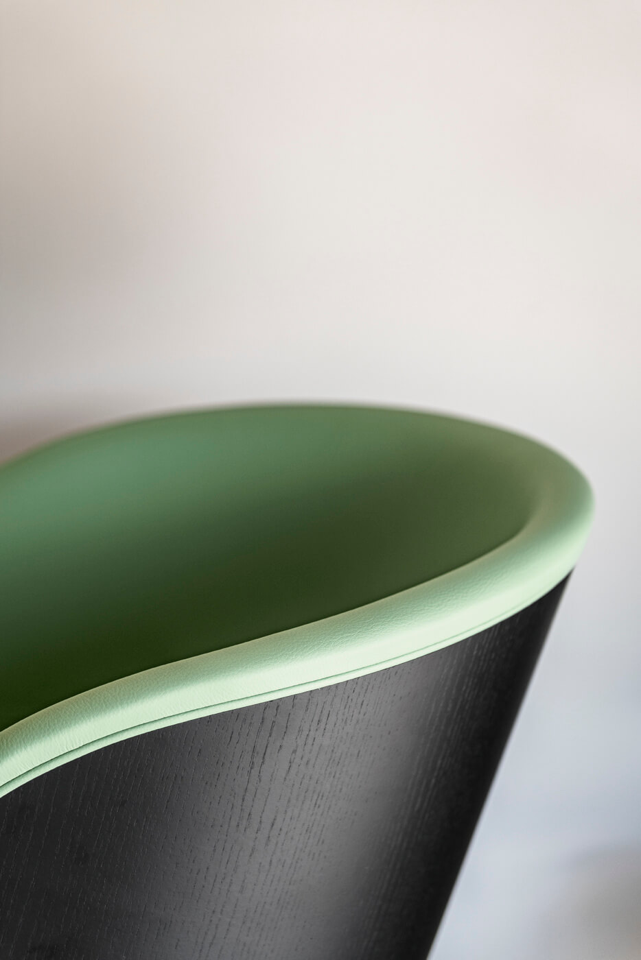 Danny armchair detail with black wood shell back and green leather seat