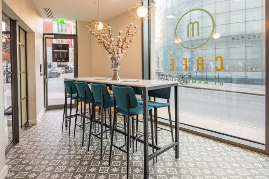 The Joe bar stools with metal legs and fabric upholstery are placed close to the counter of hotel Indigo's M Cafè in Manchester